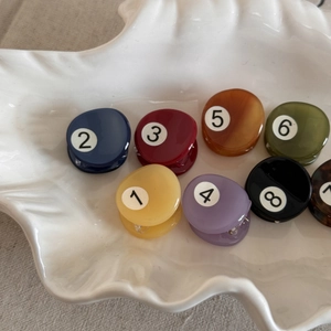 Macro shot of colorful billiard ball mini hair claws in a decorative shell tray