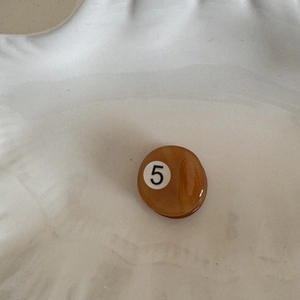 Detail view of miniature amber orange number 5 billiard ball hair clip accessory