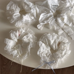 Detail of white lace hair scrunchies with ribbons and pearls in a soft vintage style