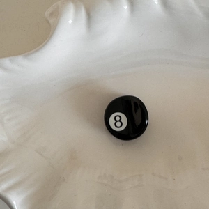 Detail view of mini acetate billiard ball number 8 hair claw clip on a white plate