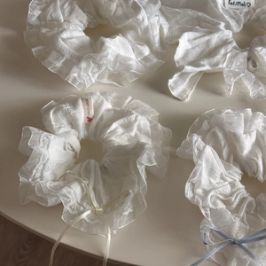 Detailed macro view of white lace scrunchies with elegant pearls and delicate ribbon bows