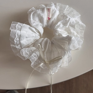 Detail of white lace scrunchie with a ribbon bow and handmade fabric label decoration