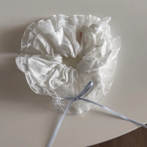 Detailed view of white lace scrunchie with a delicate light blue ribbon bow accessory
