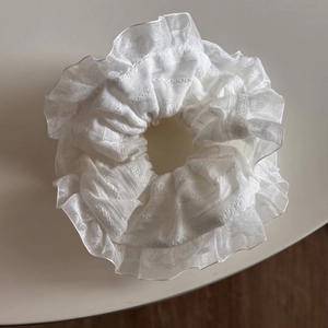 Detail of white lace hair scrunchie featuring delicate ruffled edges and organza texture