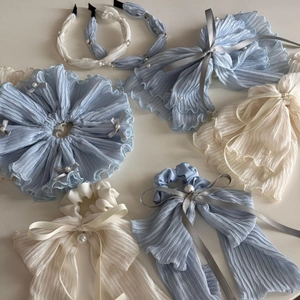 Detail of light blue pleated fabric hair scrunchies and headband with pearl bow accent