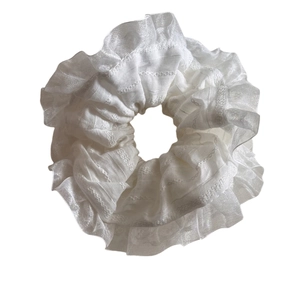 Elegant white scrunchie with delicate lace edges and textured fabric for hair styling