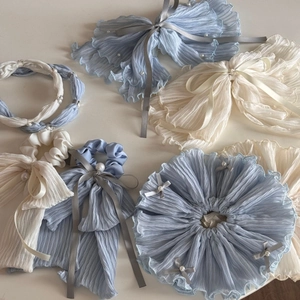 Detailed flat lay of blue chiffon scrunchies and bow hair clips with pearls