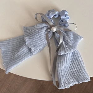 Detail of light blue pleated fabric scrunchie with grey bow and large white pearl accent