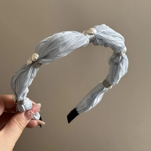 Close-up of light blue fabric scrunchie with white pearls and sparkling rhinestones