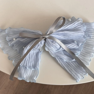 Close-up of light blue pleated fabric hair scrunchie with pearls and silk bow detail
