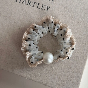 Close-up of polka dot mesh hair scrunchie with lace edges and a large faux pearl