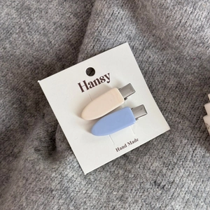Dettaglio di fermagli per capelli blu pastello e crema opachi su sfondo in maglia morbida
