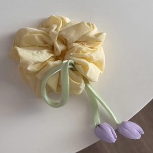 Detail of light yellow scrunchie with green ribbon and purple tulip charms for ponytails