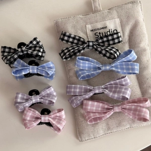 Detail of sweet plaid bow hair clips in four colors on a rustic studio background