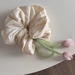 Detail view of cream tulip scrunchie with soft satin flower charms and green stems