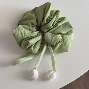 Detail of avocado green scrunchie with silky ribbons and white tulip floral pendants