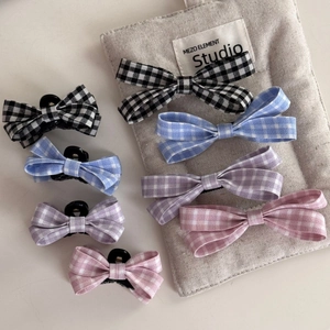 Macro detail of plaid bow hair clips in black blue purple and pink fabric texture