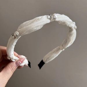 Detail of white fabric headband with delicate pearls and sparkling rhinestones