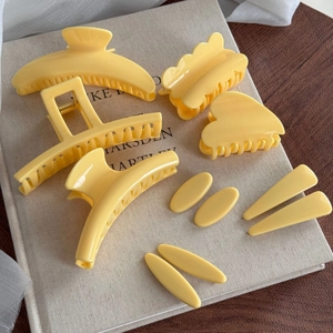 Lot de 8 pinces à cheveux jaune crème aux formes variées posées sur un livre
