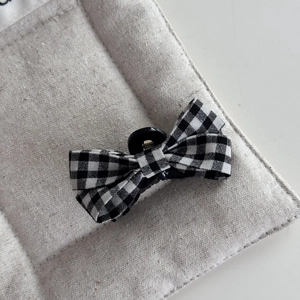 Detail of classic black and white gingham bow hair clip with fine fabric texture and small grip