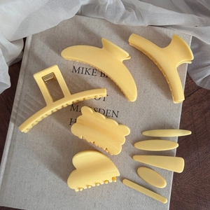 Lot de pinces à cheveux géométriques jaune mat et barrettes sur un livre