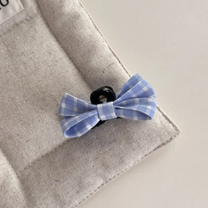 Detail of blue and white plaid bow hair clip with black plastic claw and metal spring