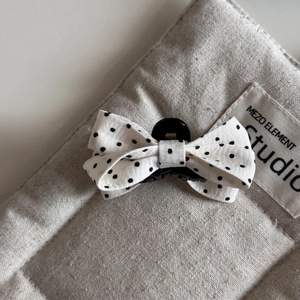 Detail view of a French style polka dot bow hair claw clip on a beige textured surface