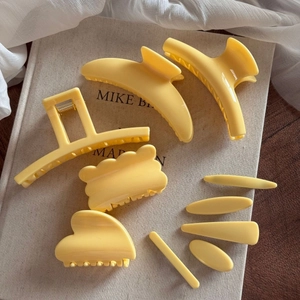 Ensemble de 8 pinces à cheveux et barrettes jaune mat sur un fond en tissu minimaliste