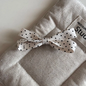 Close-up of a white polka dot bow hair clip made of linen fabric with quilted texture details