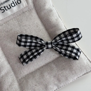 Detailed view of sweet black and white gingham bow hair clip on a soft quilted fabric