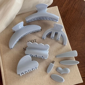 Detail view of light blue acetate hair clip set featuring marble texture on a book background