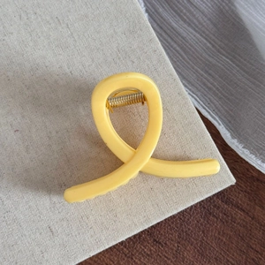 Vue détaillée de la pince à cheveux en résine jaune vif avec ressort en métal doré
