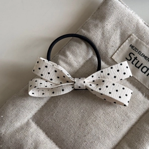 Detailed view of the woven fabric texture on a cream bow hair clip with black polka dots