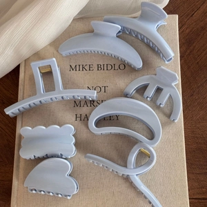 Detailed set of 7 matte light blue hair claws in various shapes on a beige fabric background