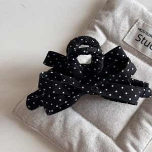 Detail shot of a French style black and white polka dot bow hair claw clip on soft fabric