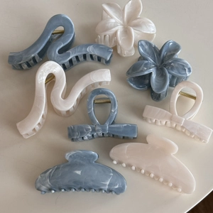Flat lay of large marble pattern claw clips in blue-grey and cream acetate finishes