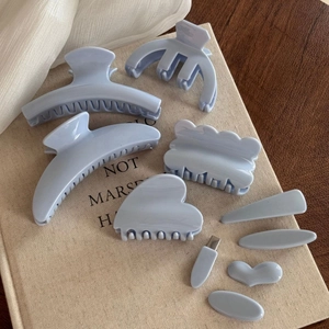 Flat lay of light blue hair claw clips and barrettes set on a beige textured book
