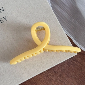 Détail de la pince à cheveux jaune mate avec ressort doré robuste et design torsadé épuré