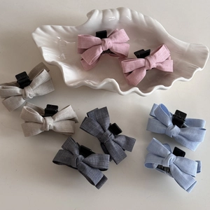 Set of 8 colorful linen bow hair clips in pink, grey, and blue on white background