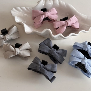 Set of pastel bow hair claws in pink, grey, and blue on a minimalist white background