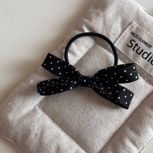 Close-up of French vintage black fabric bow hair tie with white polka dots and soft texture