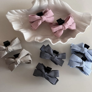 Set of 8 woven bow hair clips in pink, grey and blue on a decorative white shell tray