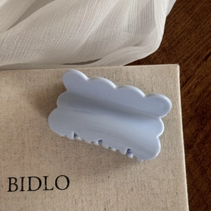Detailed view of the light blue hair claw clip with glossy finish and wavy edge design