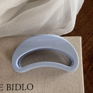Detailed macro view of the light blue matte crescent moon hair claw clip on fabric