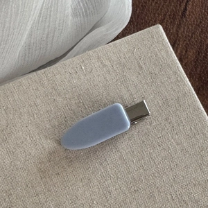 Detail view of a matte light blue hair clip with a silver duckbill metal clasp