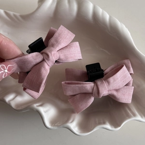 Detail view of pink fabric bow hair claw clips on a white ceramic shell tray