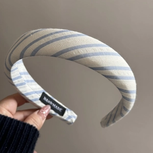 Gros plan détaillé du serre-tête en tissu rayé bleu et blanc avec étiquette faite main
