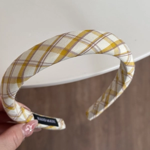 Dettaglio del cerchietto giallo a quadri con trama del tessuto ed etichetta a mano