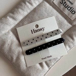 Detailed view of handmade black and white polka dot fabric hair clips on a card