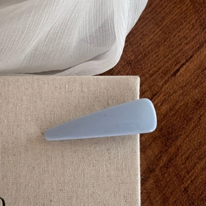 Close-up of minimalist light blue hair clip on a textured canvas and wooden background